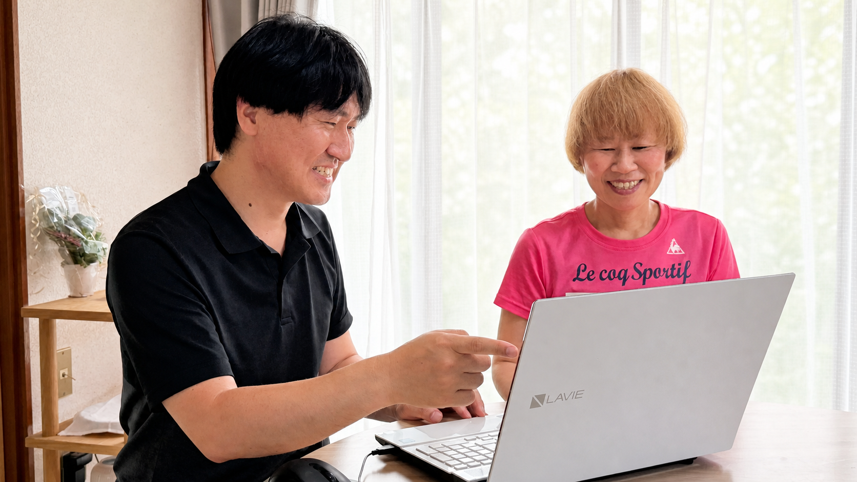 明るいご自宅でお客様にパソコンの操作を説明する大澤壮登